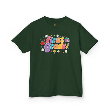 Navy blue t-shirt with 'First Grade!' design on a white background. TEEZOCA t-shirt showing a paper airplane, stars, pencil, apple, and books for a 1st grade shirt for boys.