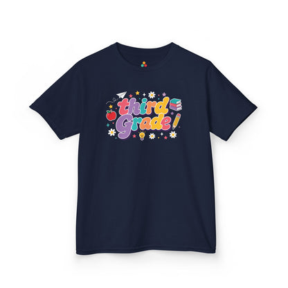 Navy blue t-shirt with 'third Grade!' text and graphics on a white background. TEEZOCA t-shirt with colorful Third Grade bubble letters, school icons, daisies, stars, and a playful third grade shirt design.