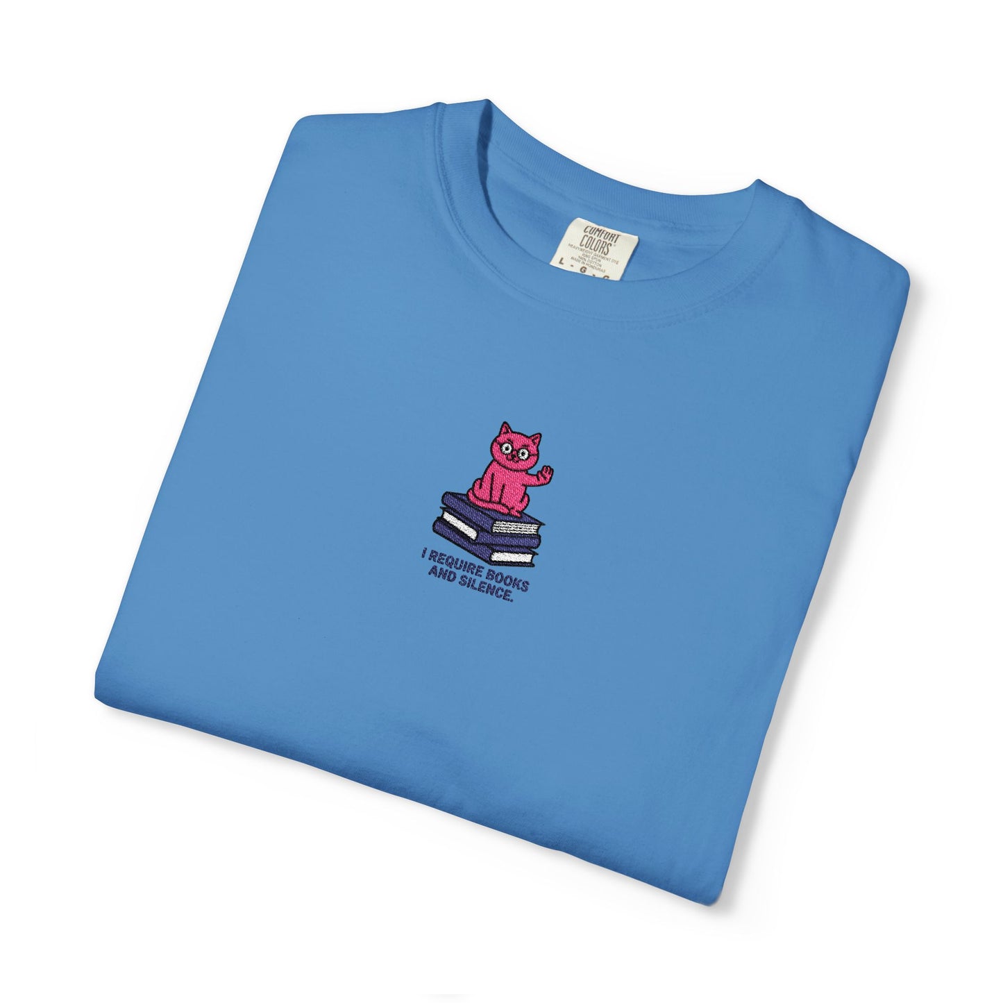 Royal Caribe Comfort Colors®  shirt featuring an embroidered pink cat sitting on books with the saying “I Require Books and Silence.”
