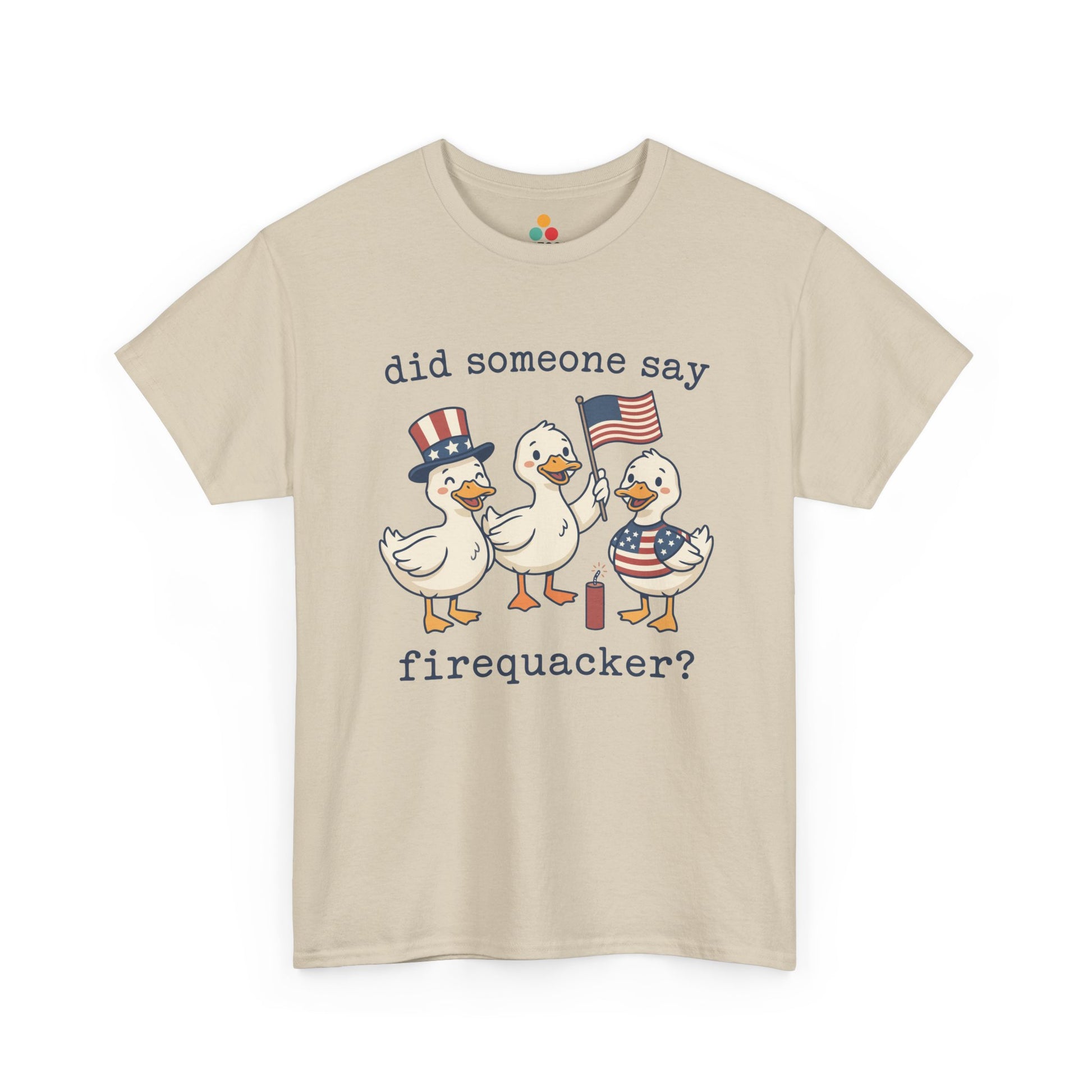 beige  TEEZOCA T-shirt featuring three cartoon patriotic ducks — one in an Uncle Sam hat, one holding a US flag, and one in a stars-and-stripes outfit — around a firecracker with the text "did someone say firequacker?" printed above and below.

