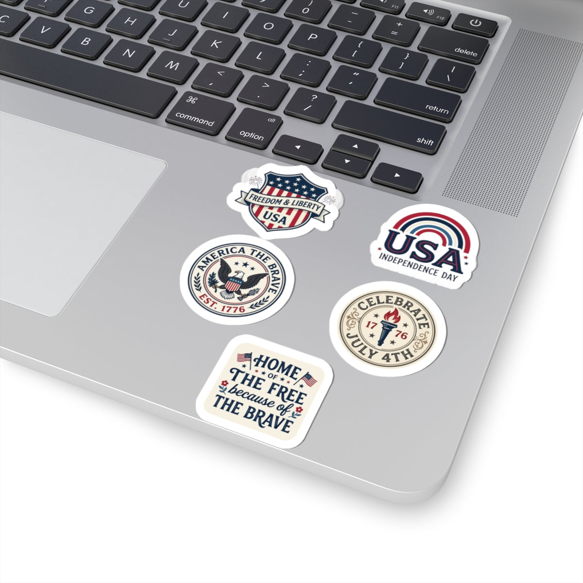 TEEZOCA 4th of July sticker sheets applied smoothly to the corner corner of a grey modern laptop.