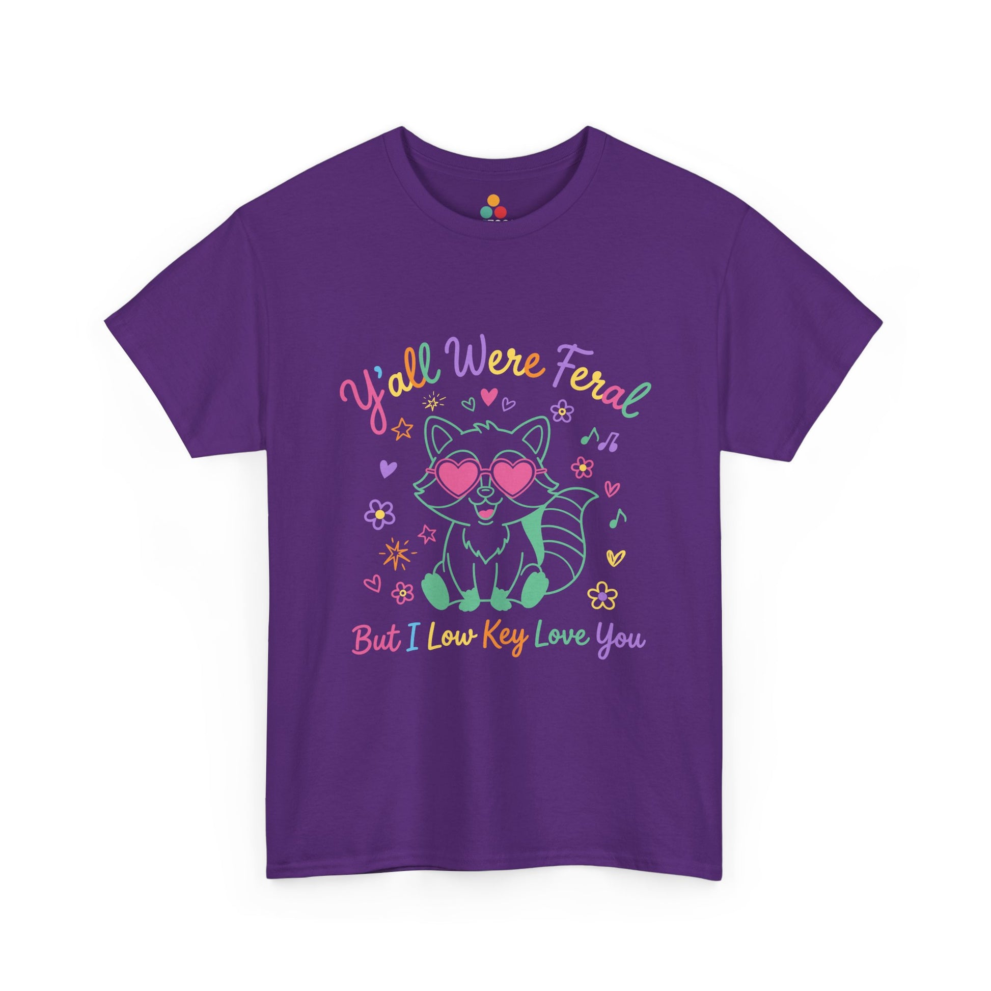 TEEZOCA t-shirt featuring Y'all Were Feral But I Low Key Love You artwork with a colorful raccoon teacher graphic.
