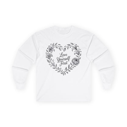 TEEZOCA unisex long-sleeve t-shirt with love yourself first floral wreath artwork White sweatshirt with floral heart design and 'Love Yourself First' text on a white background