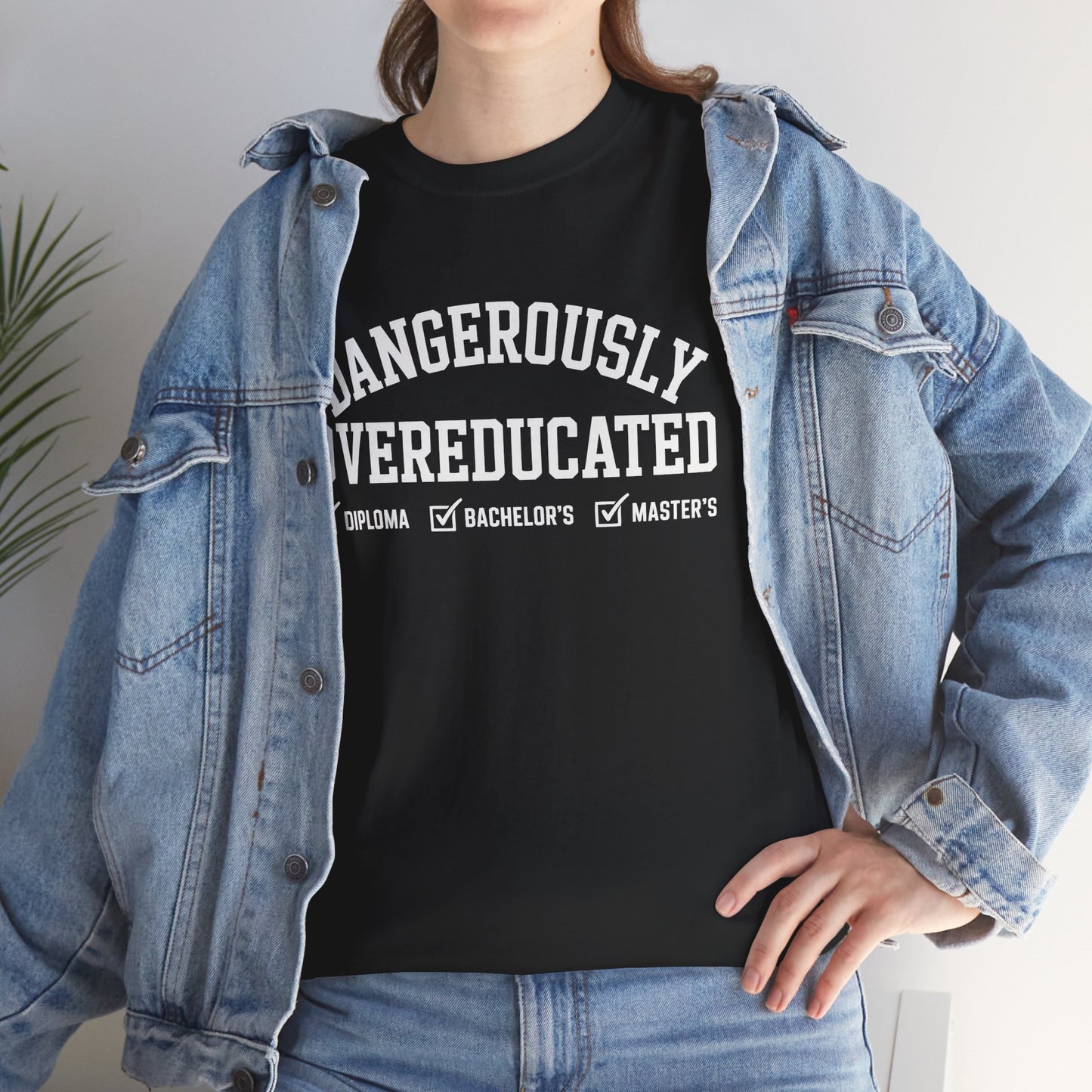 Woman in a denim jacket styling a black TEEZOCA Dangerously Overeducated academic humor tee.