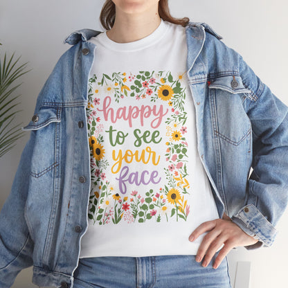 Women wearing a White T-shirt featuring the phrase “Happy to See Your Face” in pastel lettering framed by a floral border with sunflowers and wildflowers.

