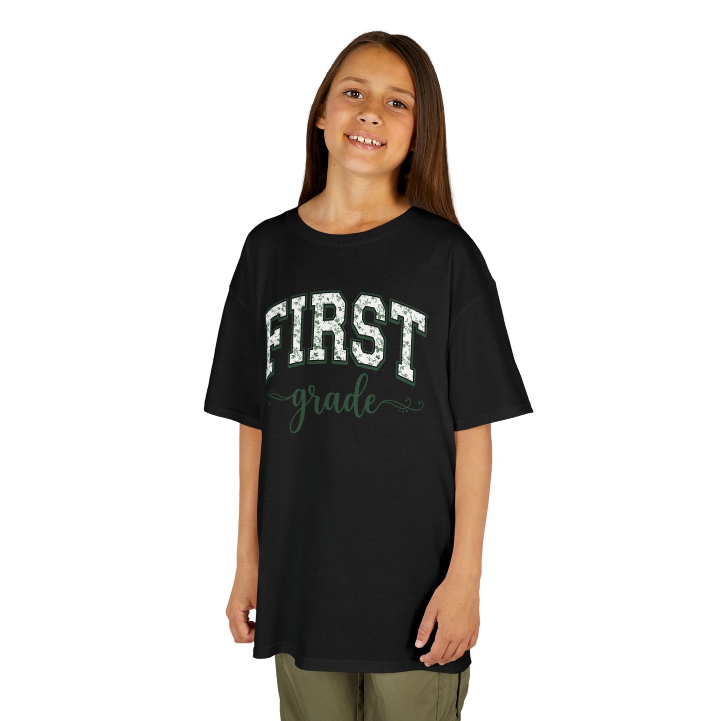 Young girl wearing a black t-shirt with 'FIRST grade' text on a white background. Floral first grade kids tee from TEEZOCA reading first grade in arched varsity type, a cute back to school shirt.
