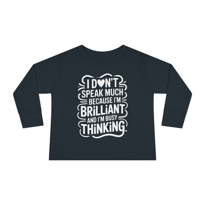 Black toddler long sleeve tee featuring autism acceptance message “I don’t speak much because I’m brilliant and I’m busy thinking” in white lettering.