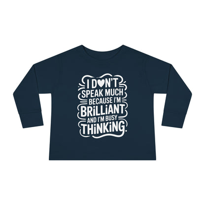 Navy toddler long sleeve shirt with hand-lettered “I don’t speak much because I’m brilliant and I’m busy thinking” design for autistic and neurodivergent kids.