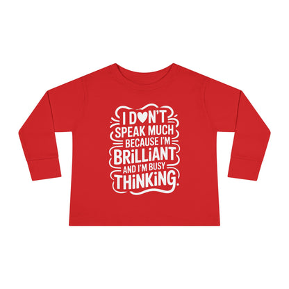 Red toddler long sleeve autism awareness top displaying bold white “I don’t speak much because I’m brilliant and I’m busy thinking” quote.