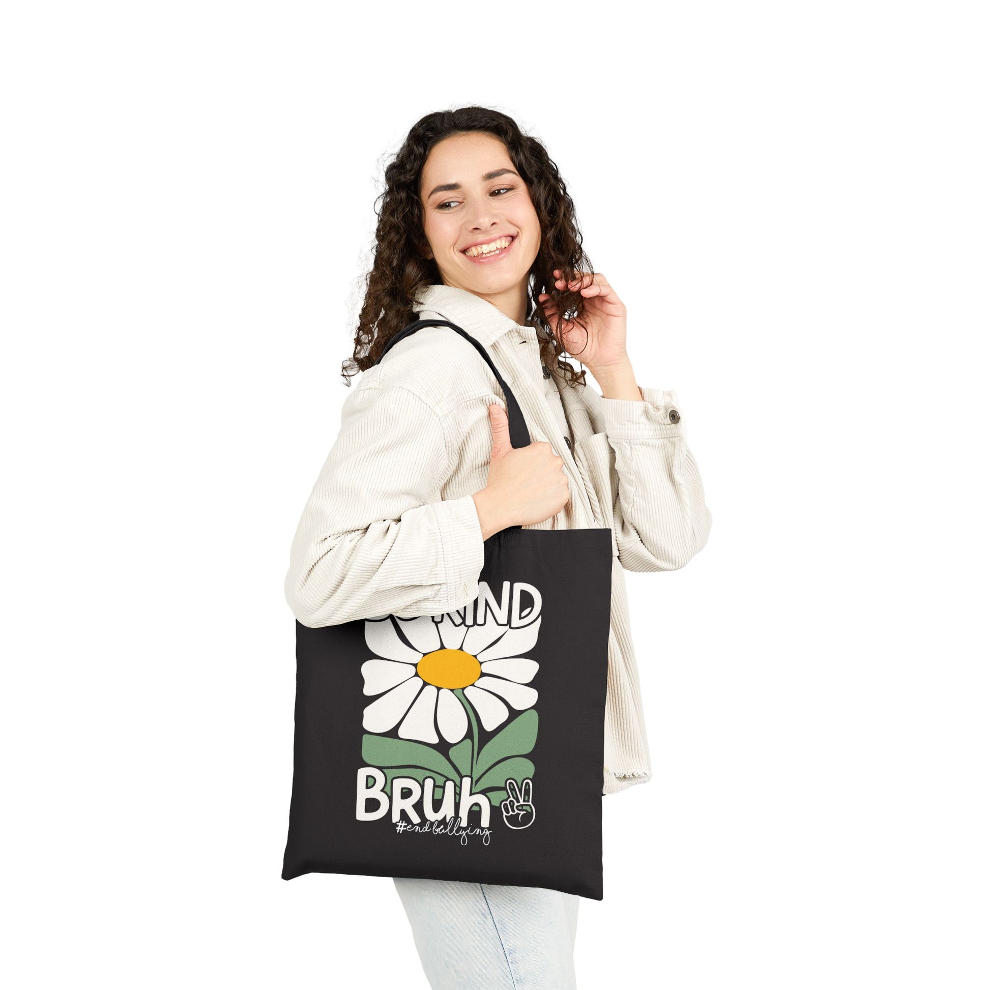 “Female model holding black canvas tote showing Be Kind Bruh daisy and peace sign”