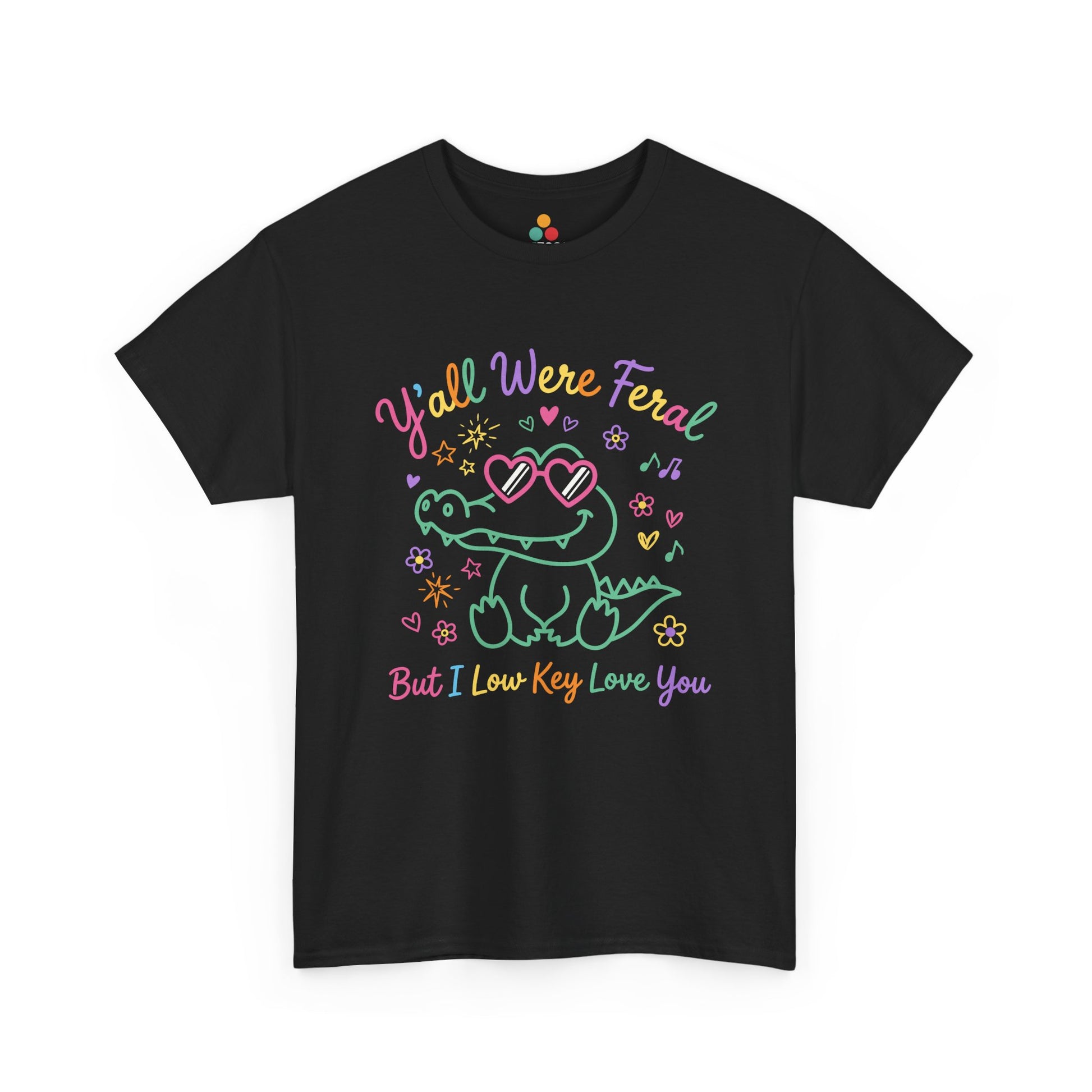 black  T-shirt featuring a cute neon crocodile wearing heart-shaped sunglasses surrounded by colorful stars and flowers, with rainbow text reading "Y'all Were Feral But I Low Key Love You" — a funny last day of school teacher gift shirt.

