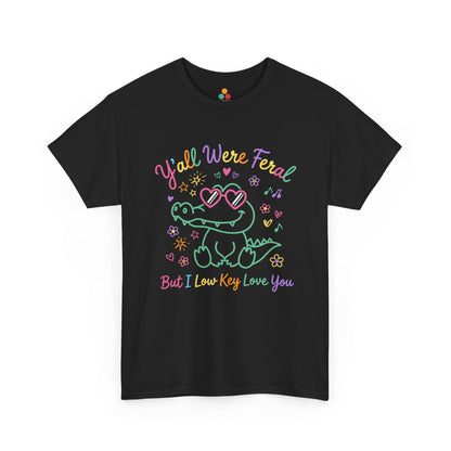 black  T-shirt featuring a cute neon crocodile wearing heart-shaped sunglasses surrounded by colorful stars and flowers, with rainbow text reading "Y'all Were Feral But I Low Key Love You" — a funny last day of school teacher gift shirt.

