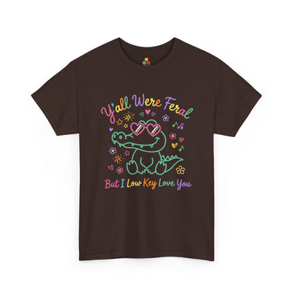 brown T-shirt featuring a cute neon crocodile wearing heart-shaped sunglasses surrounded by colorful stars and flowers, with rainbow text reading "Y'all Were Feral But I Low Key Love You" — a funny last day of school teacher gift shirt.

