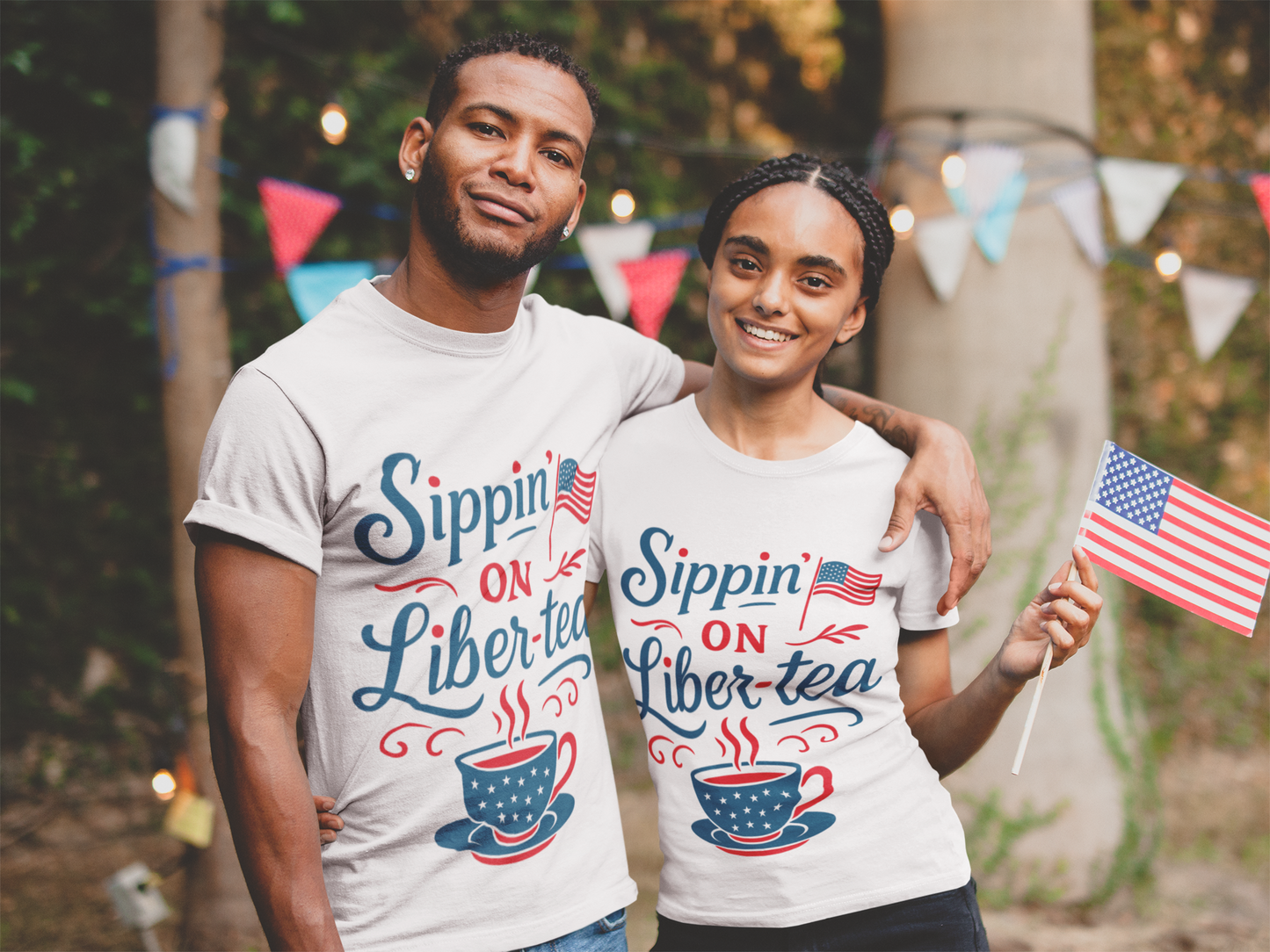  Smiling couple wearing matching “Sippin’ on Liber-tea” shirts, holding an American flag at a festive outdoor July 4th celebration—perfect for Fourth of July, Memorial Day, and patriotic tea lovers.